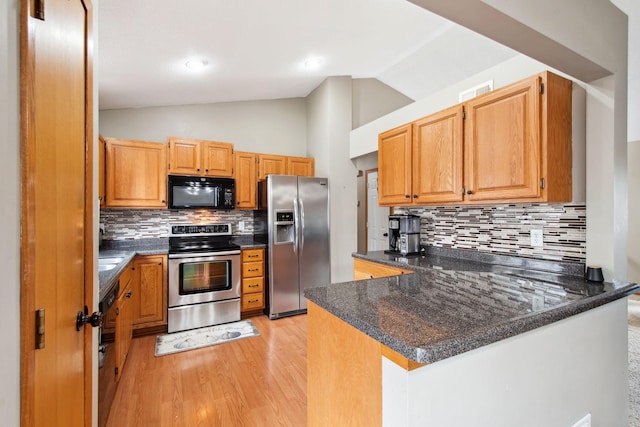 kitchen featuring tasteful backsplash, vaulted ceiling, black appliances, a peninsula, and light wood-style flooring