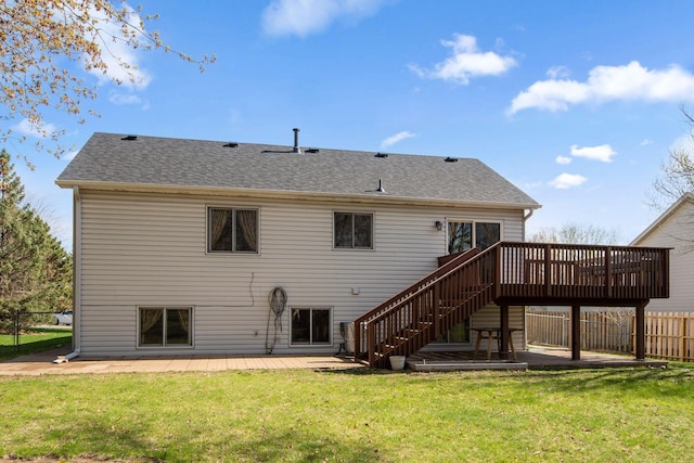 back of house with fence, a deck, stairs, a shingled roof, and a lawn