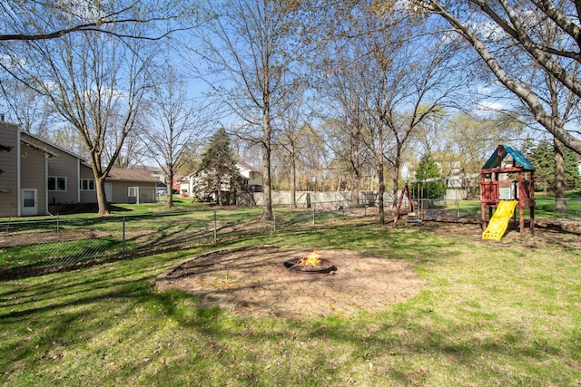 view of yard with a playground, fence, and an outdoor fire pit
