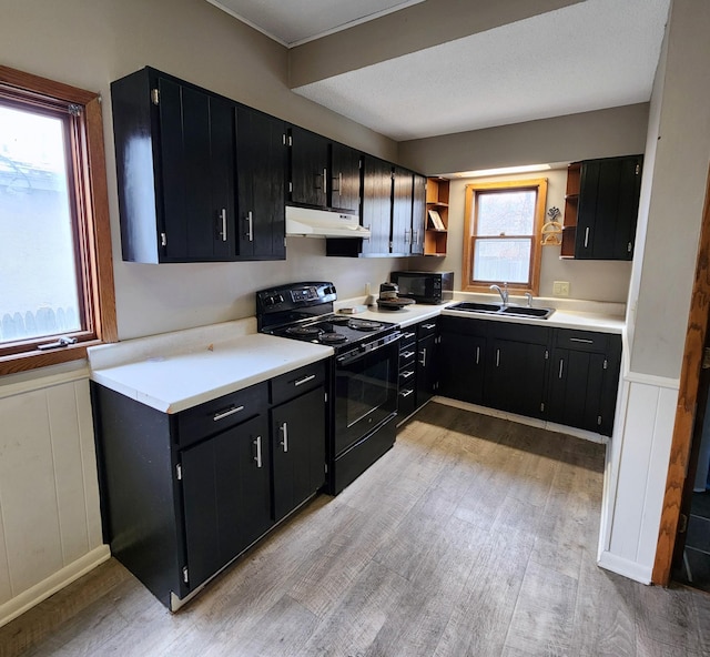 307 11th St NW, Willmar, MN 56201 - kitchen featuring open shelves, under cabinet range hood, dark cabinets, a sink, and black appliances
