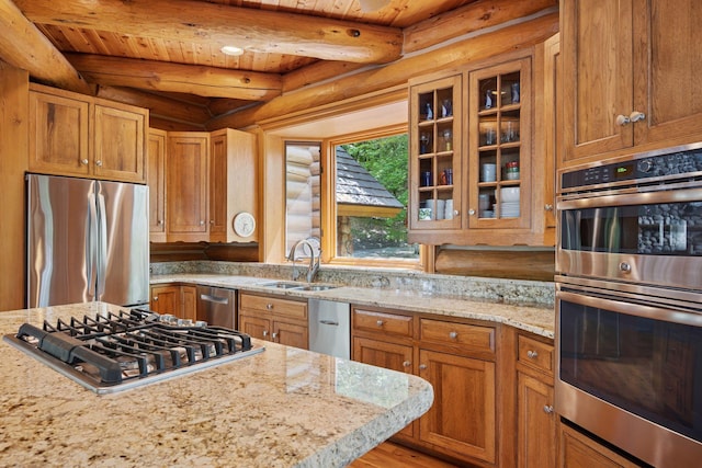 6070 Pilger Ave NW, Annandale, MN 55302 - kitchen featuring appliances with stainless steel finishes, log walls, a sink, light stone countertops, and glass insert cabinets