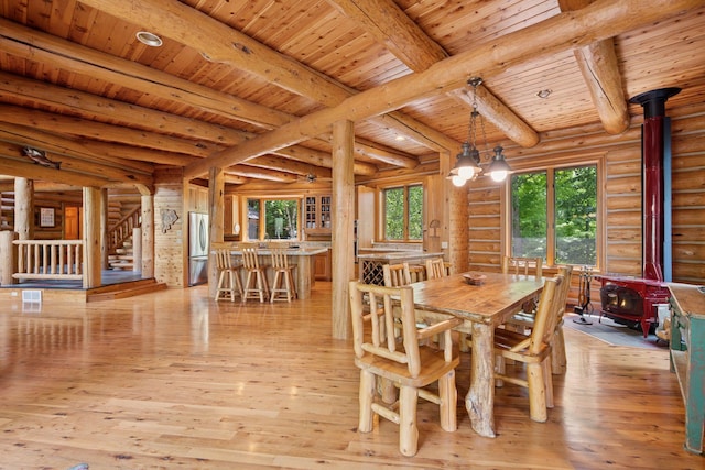 6070 Pilger Ave NW, Annandale, MN 55302 - dining area with a wood stove, wood ceiling with exposed beams, log walls, light wood finished floors, and stairway