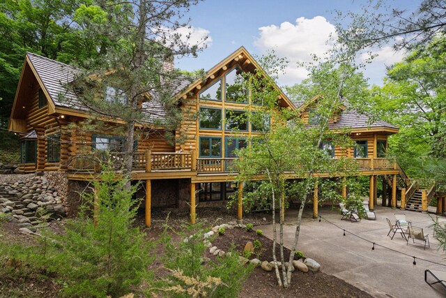 6070 Pilger Ave NW, Annandale, MN 55302 - back of property with log siding, stairs, a patio, and a deck
