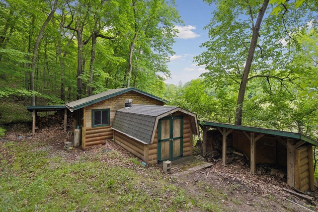 6070 Pilger Ave NW, Annandale, MN 55302 - back of house with an outbuilding, a gambrel roof, a forest view, and log veneer siding