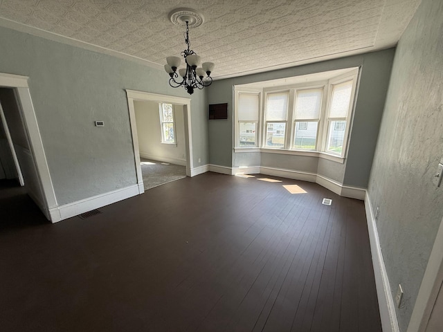 300 4th St SW, Little Falls, MN 56345 - unfurnished dining area featuring a chandelier, a textured wall, dark wood-type flooring, an ornate ceiling, and baseboards