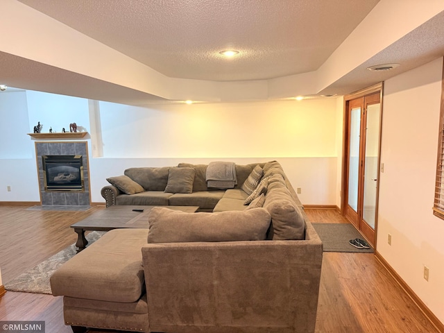 living room with a textured ceiling, baseboards, wood finished floors, and a fireplace