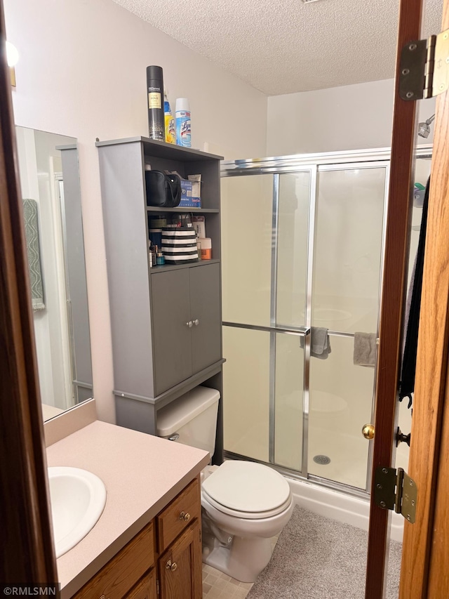 full bathroom featuring vanity, a textured ceiling, a stall shower, and toilet