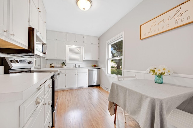 1759 Flandrau St, Maplewood, MN 55109 - kitchen featuring appliances with stainless steel finishes, light wood-style flooring, light countertops, and white cabinets