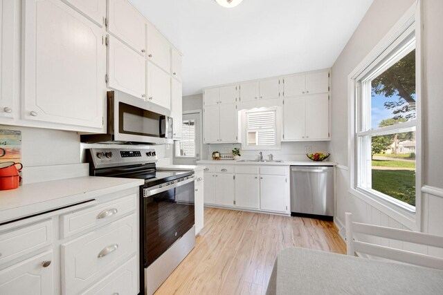 1759 Flandrau St, Maplewood, MN 55109 - kitchen with appliances with stainless steel finishes, light countertops, light wood finished floors, and white cabinetry