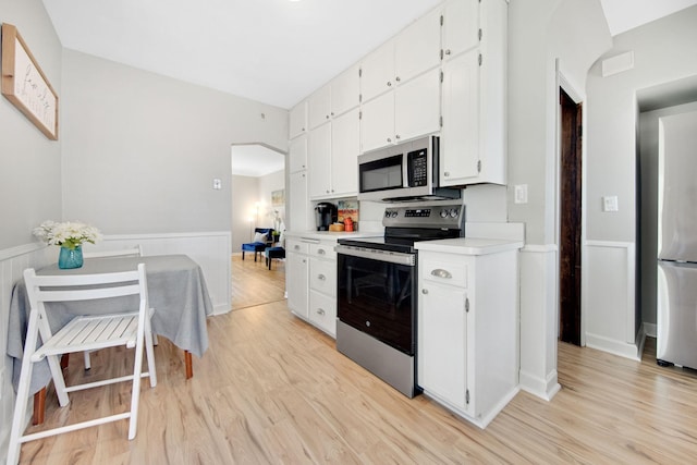 1759 Flandrau St, Maplewood, MN 55109 - kitchen with stainless steel appliances, wainscoting, light wood-style flooring, white cabinetry, and light countertops