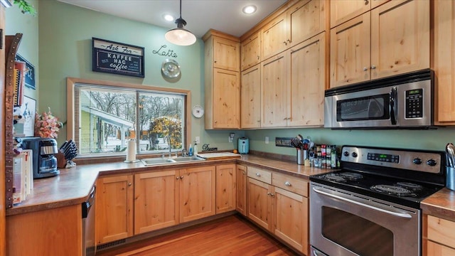 1007 Van Dyke Rd NW, Alexandria, MN 56308 - kitchen with stainless steel appliances, a sink, light brown cabinets, light wood finished floors, and pendant lighting