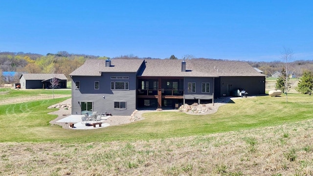 back of house featuring a lawn, a patio, and a fire pit