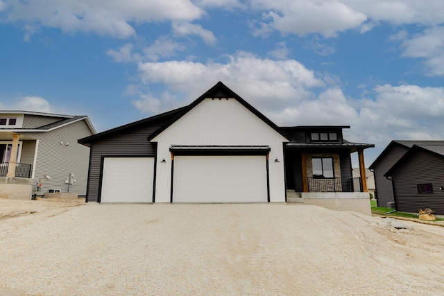 1824 Brandt Dr NE, Byron, MN 55920 - view of front of house featuring a garage, gravel driveway, a porch, and board and batten siding