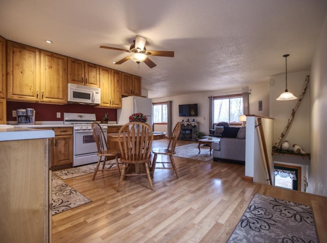 kitchen with ceiling fan, light countertops, open floor plan, light wood-style floors, and white appliances