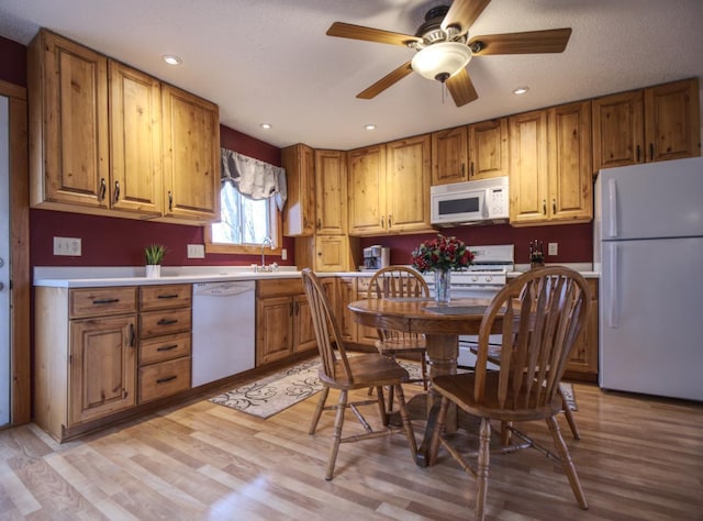 kitchen featuring white appliances, brown cabinets, a sink, and light wood-style flooring