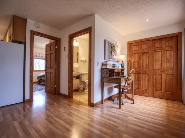 corridor featuring baseboards, a textured ceiling, and wood finished floors
