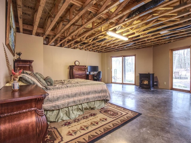 bedroom featuring access to outside, multiple windows, a wood stove, and finished concrete flooring