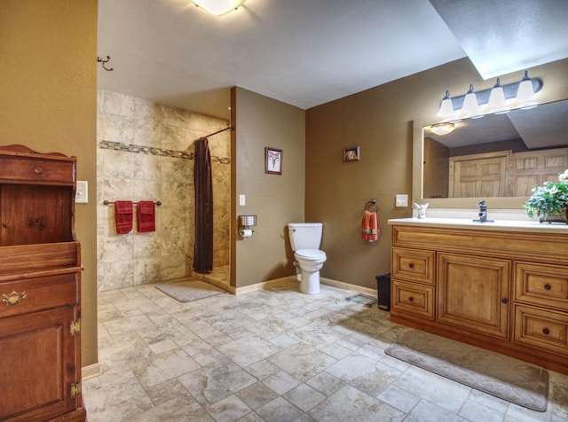 bathroom featuring vanity, baseboards, a tile shower, and toilet