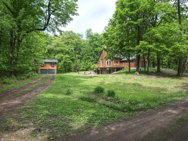 14534 290th Ave, Sampson Twp, WI 54757 - view of green lawn featuring a deck, an outbuilding, driveway, a forest view, and an attached garage