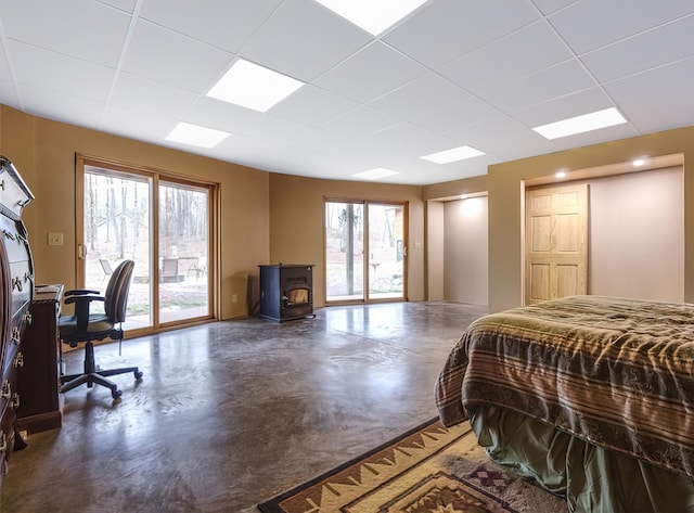 14534 290th Ave, Sampson Twp, WI 54757 - bedroom with access to exterior, concrete floors, a wood stove, a paneled ceiling, and multiple windows