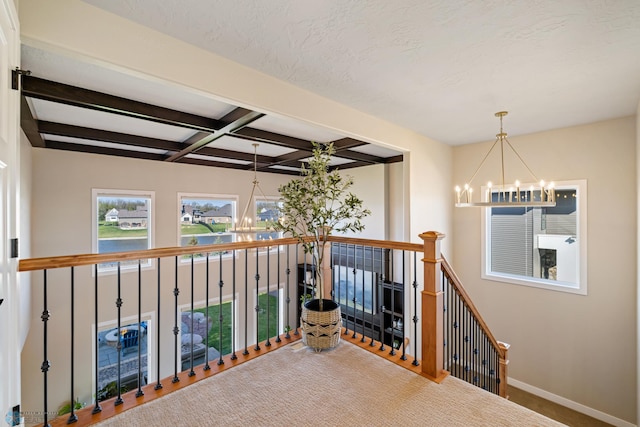 hallway featuring a chandelier, beam ceiling, a water view, baseboards, and an upstairs landing