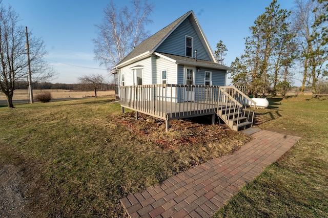 back of property with roof with shingles, a yard, and a deck