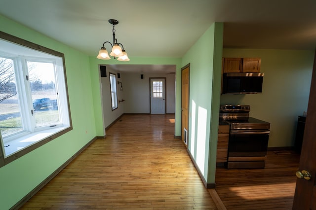 corridor with light wood finished floors, baseboards, and a chandelier