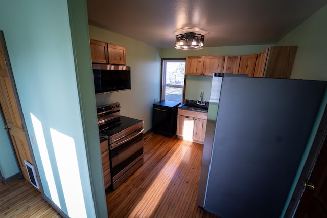 kitchen with light wood-type flooring, a sink, and appliances with stainless steel finishes