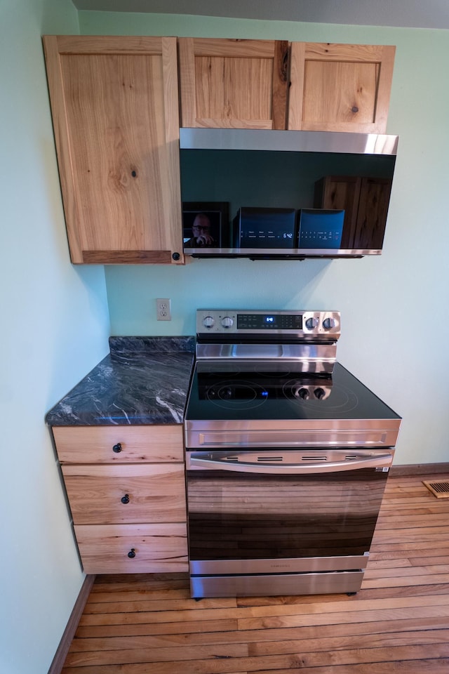 kitchen featuring light brown cabinetry, stainless steel electric range oven, baseboards, visible vents, and wood finished floors