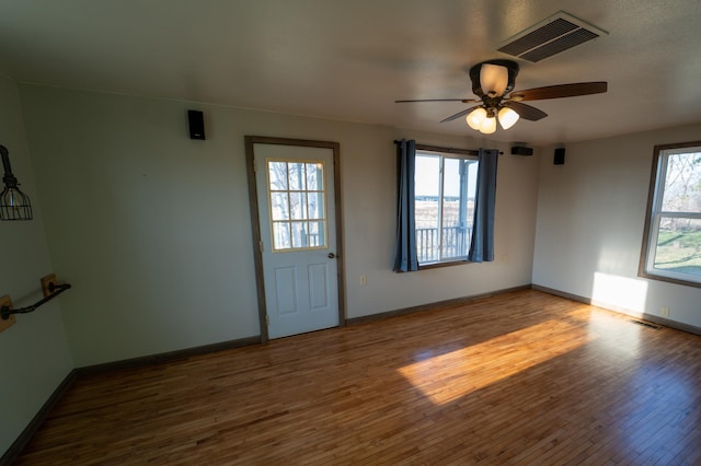 interior space featuring ceiling fan, baseboards, wood finished floors, and visible vents