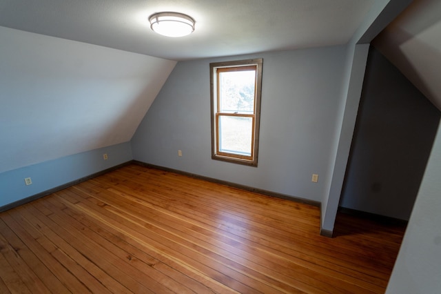 additional living space with baseboards, lofted ceiling, and hardwood / wood-style flooring