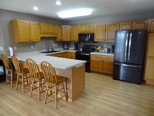 N1698 945th St, Rock Creek Twp, WI 54701 - kitchen with light countertops, a sink, light wood-style floors, black appliances, and a peninsula
