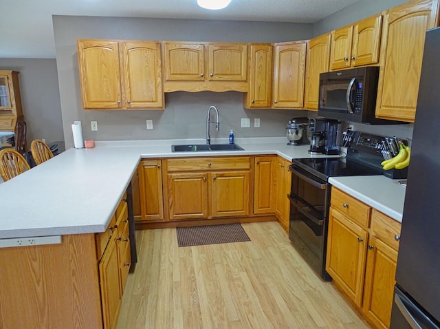 N1698 945th St, Rock Creek Twp, WI 54701 - kitchen featuring light countertops, a sink, light wood-type flooring, black appliances, and a peninsula