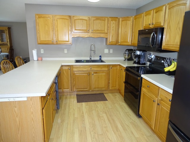N1698 945th St, Rock Creek Twp, WI 54701 - kitchen featuring light countertops, a sink, black appliances, a peninsula, and light wood-style flooring
