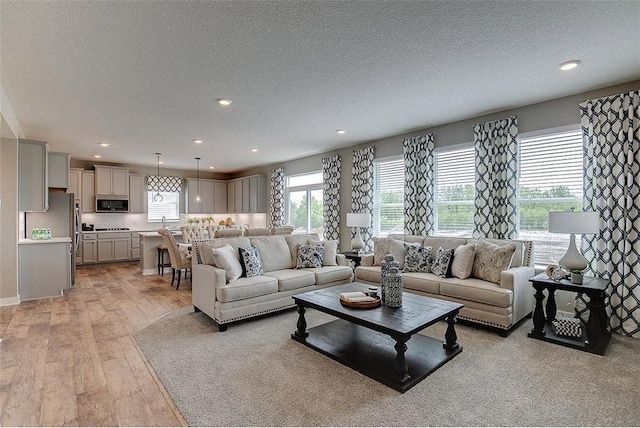 living room with recessed lighting, a textured ceiling, and light wood-style flooring
