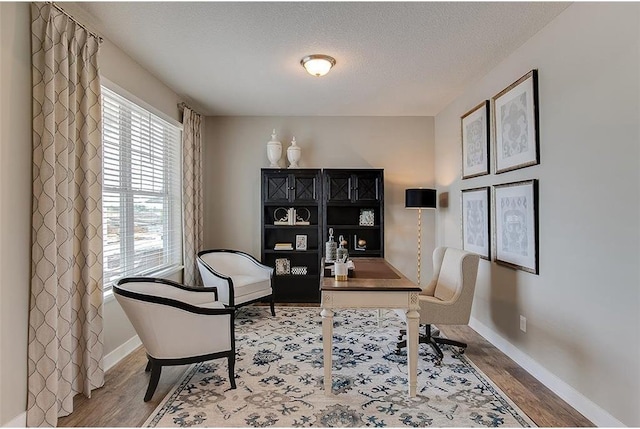 office area with a textured ceiling, baseboards, and wood finished floors