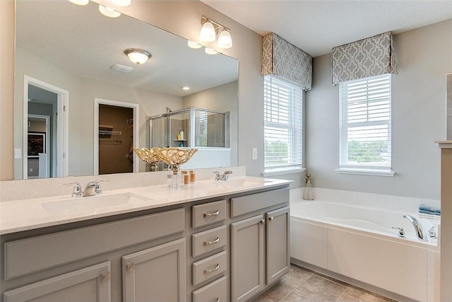 bathroom featuring a sink, double vanity, a spacious closet, a bath, and a stall shower