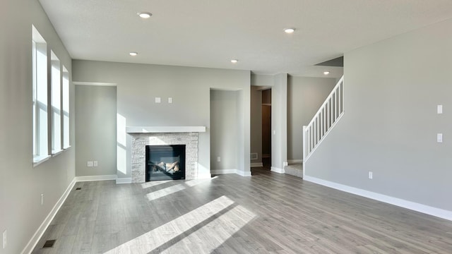 unfurnished living room with stairs, recessed lighting, baseboards, and wood finished floors