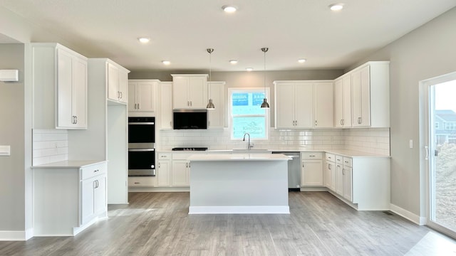kitchen with light wood-style floors, tasteful backsplash, stainless steel appliances, and white cabinetry