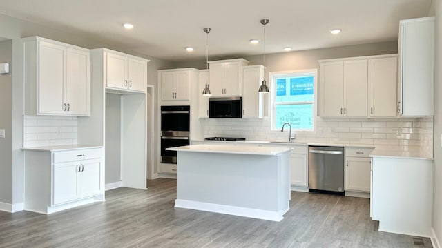 kitchen featuring light wood-type flooring, white cabinets, a sink, backsplash, and black appliances