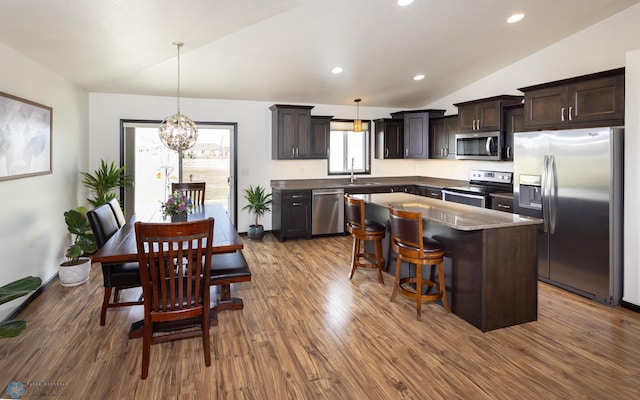 3497 50th St S, Fargo, ND 58104 - kitchen with appliances with stainless steel finishes, vaulted ceiling, dark wood-style flooring, dark brown cabinetry, and a kitchen island