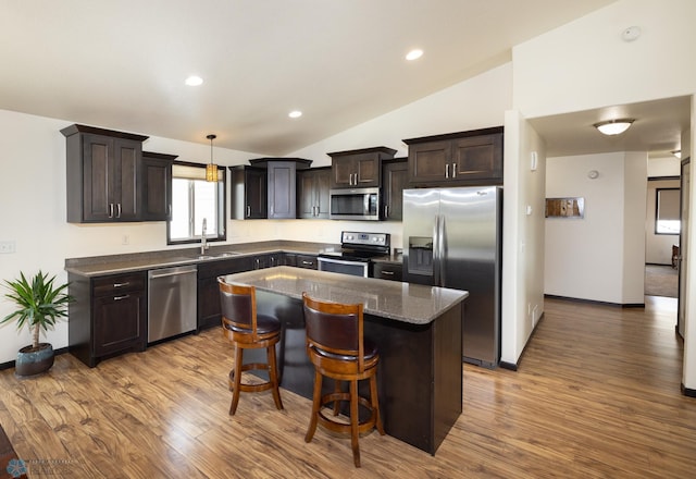 3497 50th St S, Fargo, ND 58104 - kitchen with stainless steel appliances, vaulted ceiling, dark brown cabinetry, wood finished floors, and a sink