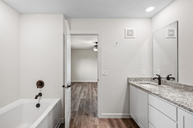 18872 Fillmore St NW, Elk River, MN 55330 - bathroom with vanity, a bath, wood finished floors, ceiling fan, and baseboards