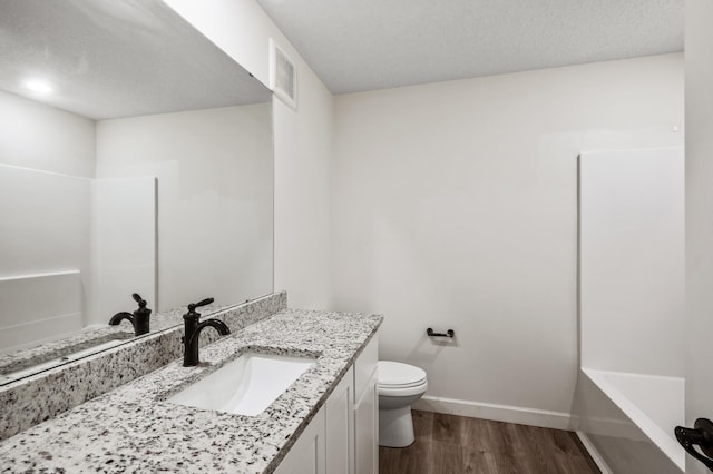18872 Fillmore St NW, Elk River, MN 55330 - bathroom featuring wood finished floors, vanity, toilet, baseboards, and a textured ceiling