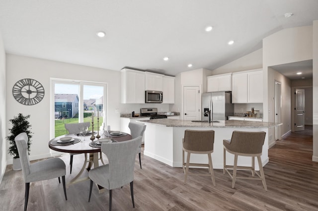 18872 Fillmore St NW, Elk River, MN 55330 - kitchen with appliances with stainless steel finishes, an island with sink, vaulted ceiling, wood finished floors, and white cabinets