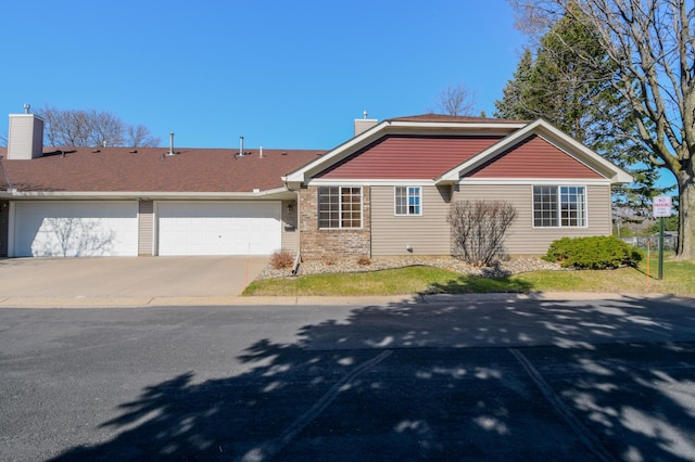 view of front of property featuring concrete driveway, a chimney, roof with shingles, and a garage