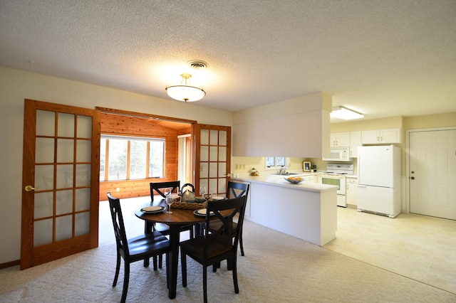 dining room with a textured ceiling, visible vents, and light carpet