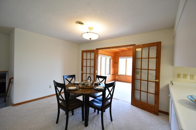 dining room featuring wooden walls, visible vents, light carpet, french doors, and baseboards