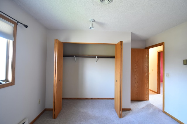 unfurnished bedroom featuring carpet flooring, multiple windows, a textured ceiling, and a closet