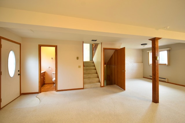 below grade area with baseboards, light colored carpet, brick wall, stairway, and a baseboard radiator